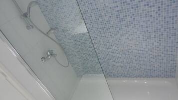 A glass-enclosed shower with a tiled wall.