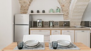 A compact kitchen with a stone arch, a coffee machine, and a refrigerator. - Terrazza Ariafina by Wonderful Italy (Ostuni)