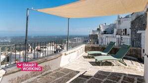 A rooftop terrace with a view of the city, two lounge chairs, and a large canopy. - Terrazza Ariafina by Wonderful Italy (Ostuni)