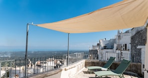 Une terrasse sur le toit offrant une vue sur la ville, deux chaises longues et un grand auvent.