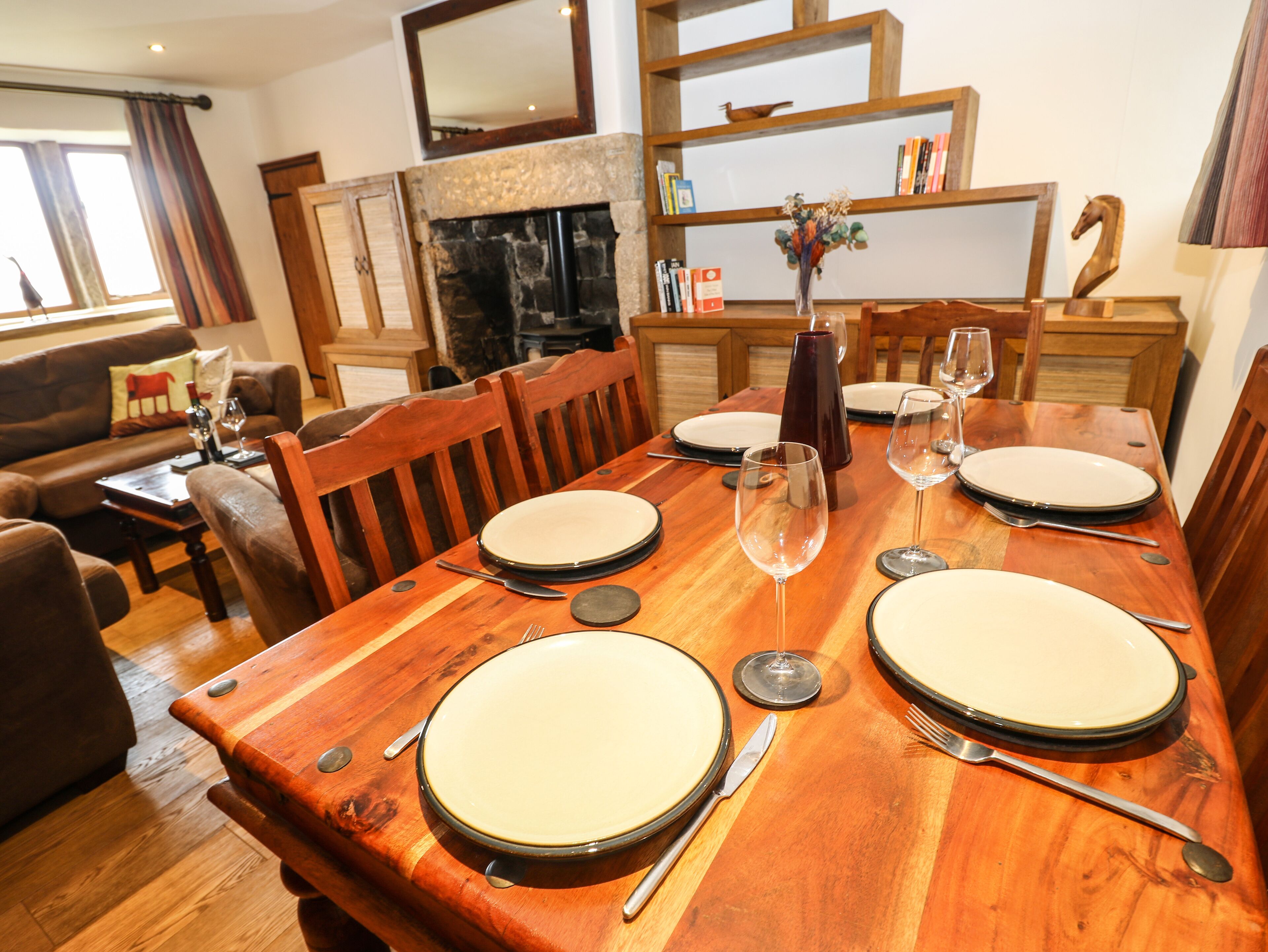 A dining area with a wooden table set for four, surrounded by wooden chairs.