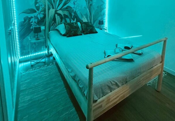 A bedroom with a bed, a bedside table, a lamp, and a wall-mounted shelf. - Appart "L'échappée Belle" Montpellier center, Train station (Montpellier)