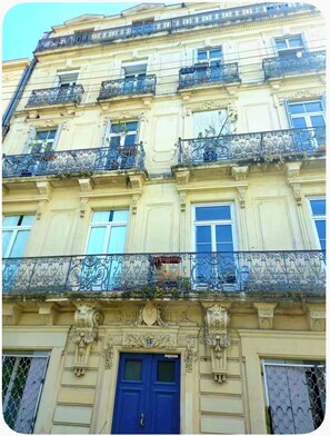 A multi-story building with ornate balconies, a prominent blue door, and classical architectural details.