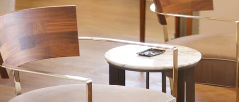 A modern dining area with a round table and two chairs with wooden backs.
