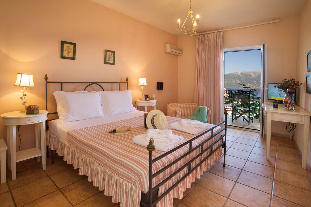 Ein Hotelzimmer mit Bett, Nachttischen, Schreibtisch, Stuhl und Blick ins Freie.