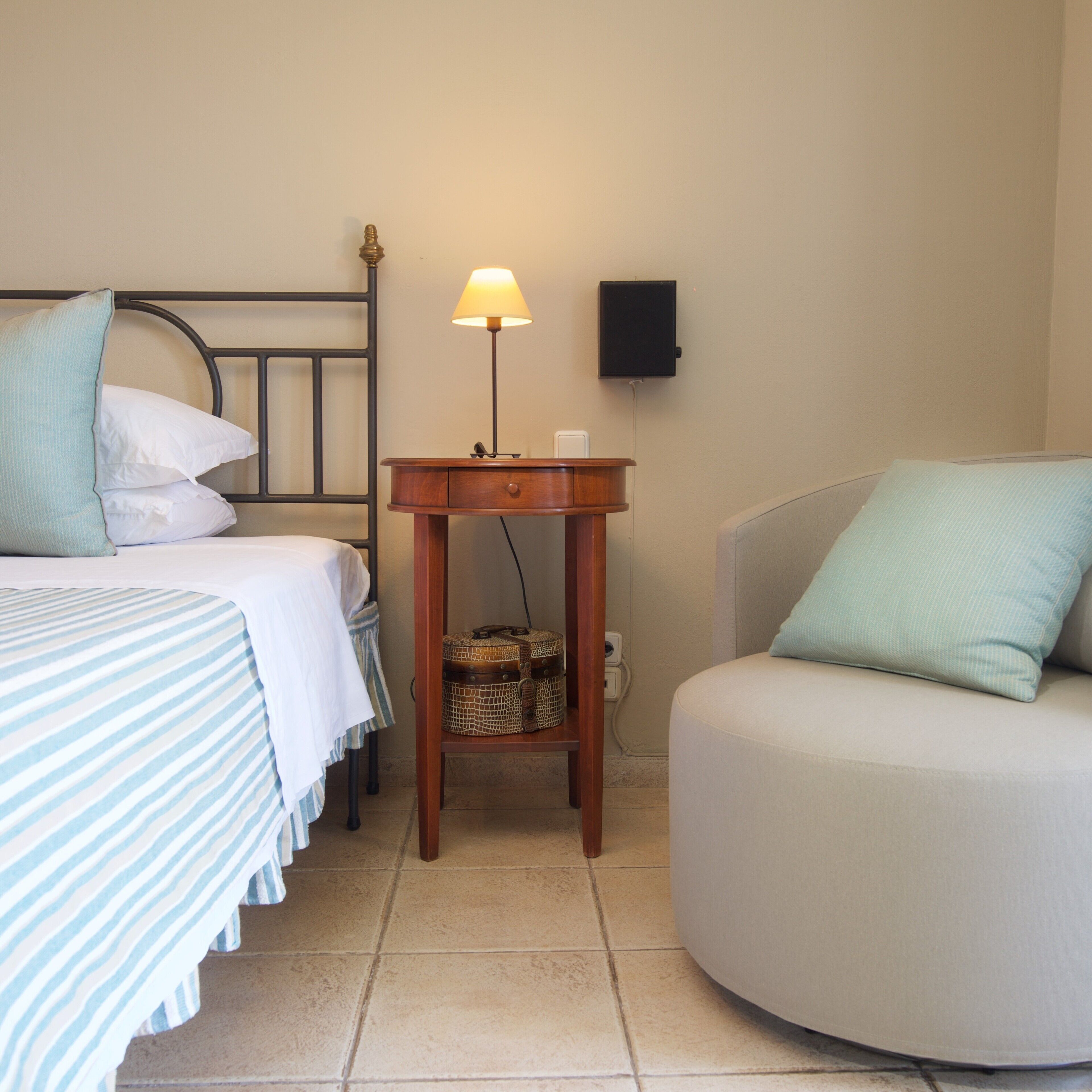 A bedroom with a bed, bedside table, lamp, and a small cabinet.