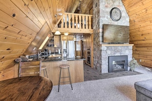 Ein Holzblockhaus-Interieur mit Küche, Essbereich und Kamin aus Stein.