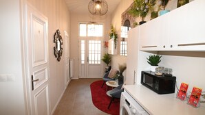 Une cuisine compacte équipée d’un lave-linge, d’un four à micro-ondes et agrémentée d’un tapis rouge.