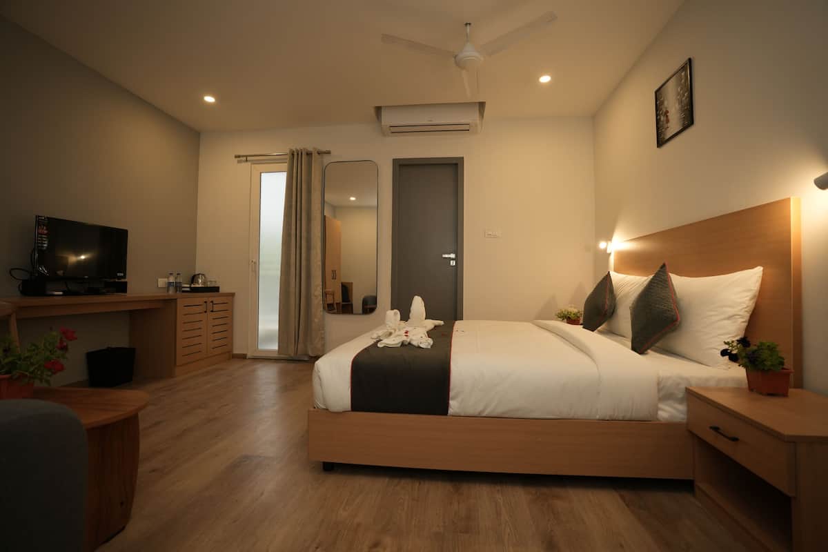 A modern hotel room with a wooden bed, bedside tables, a TV, and a ceiling fan.