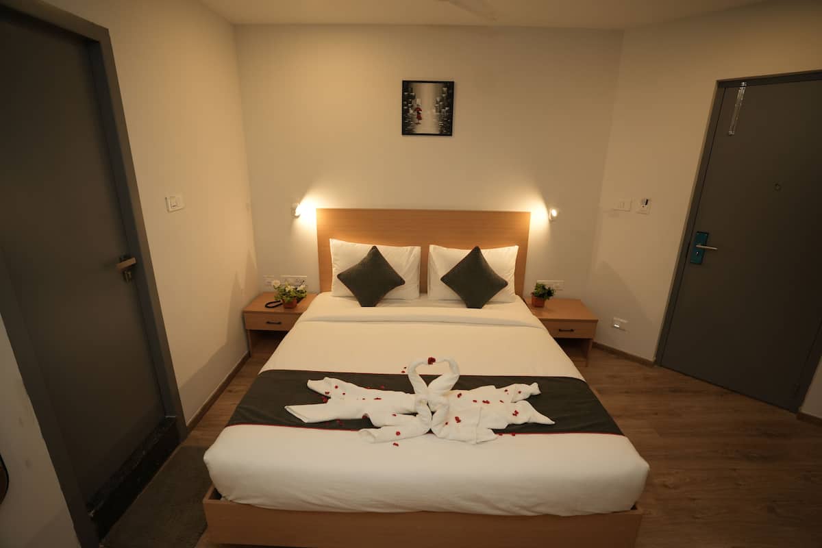 A neatly made bed with a towel arrangement in the center, a wooden headboard, two bedside tables with lamps, and a framed picture on the wall.