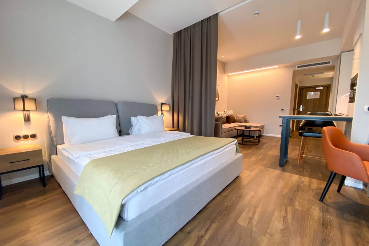 A modern hotel room with a large bed, a desk, and a chair.