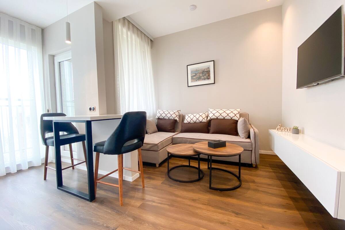 A modern living room with a sofa, two chairs, a coffee table, and a TV mounted on the wall.