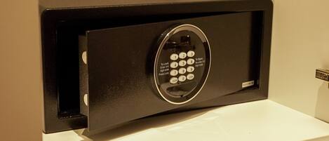 A black safe with a keypad on a white shelf.