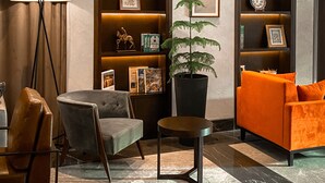 Un soggiorno moderno con un divano, una poltrona e una lampada da terra. Si notano anche mensole con oggetti decorativi e una pianta in vaso.