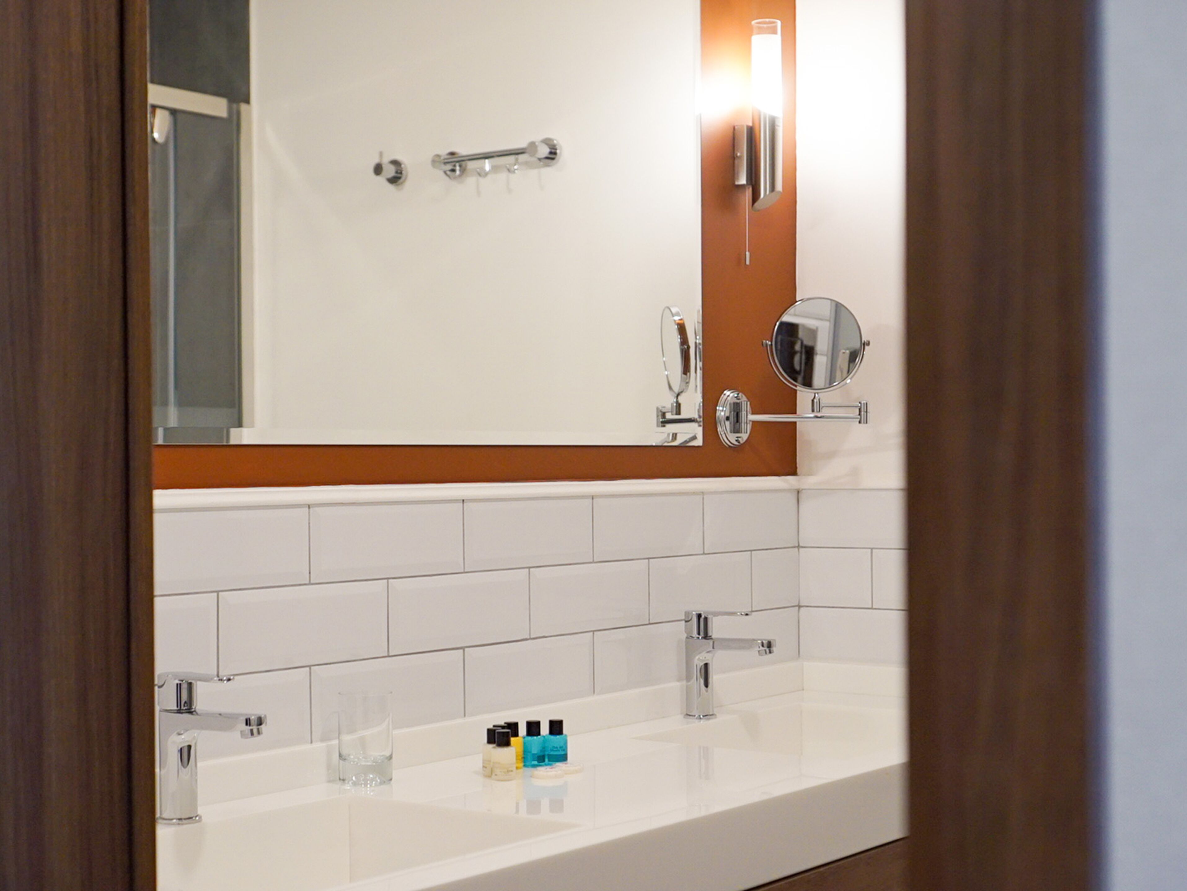 A modern bathroom with a white sink, two faucets, and a mirror.