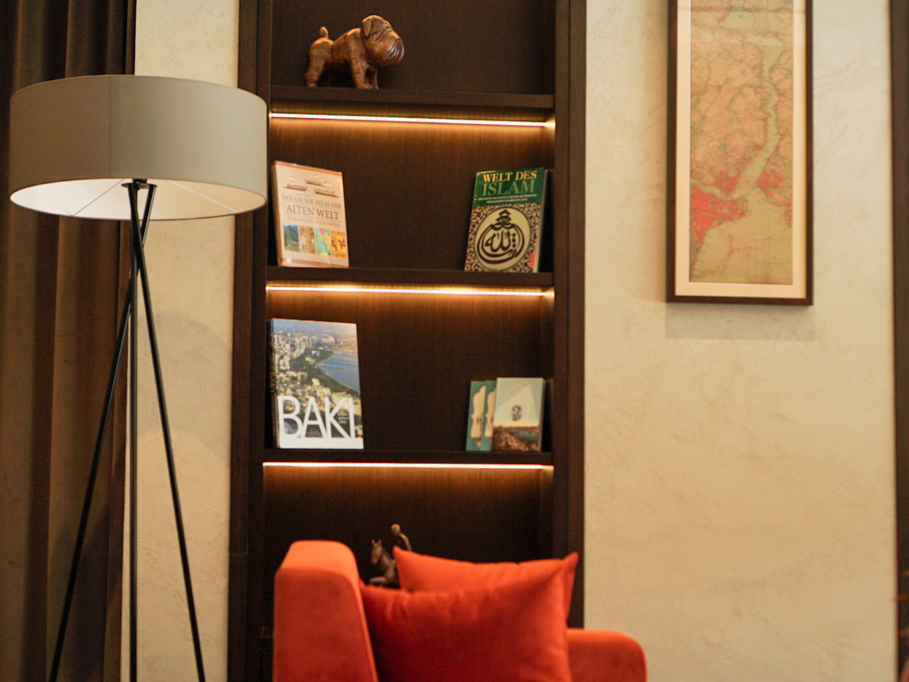 Ein Bücherregal mit Büchern und Dekoration, eine Stehlampe und eine Karte an der Wand.