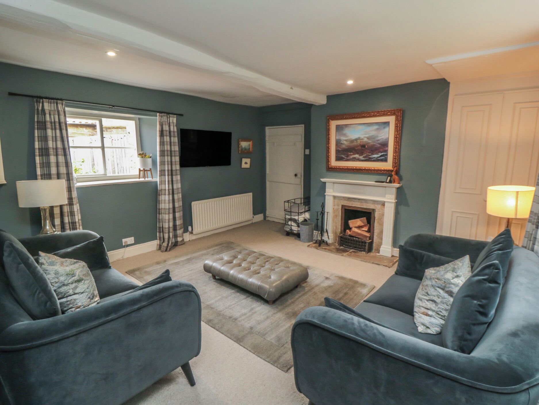 A living room with two grey sofas, a fireplace, a television, and a window with curtains.