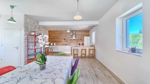 Cozinha moderna com parede de madeira, área de jantar com mesa e cadeiras, e janela com vista.