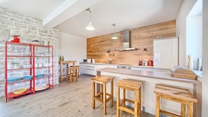 A modern kitchen with a wooden accent wall, a red shelving unit, and wooden stools. - Villa Luxoria - for 10 guests with 4 bedrooms, a private pool and a spa by MyWaycation (Jelsa)