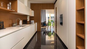 A modern kitchen with white cabinetry, a black marble countertop, and a view into a dining area with a table and chairs.
