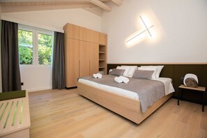 A modern bedroom with a large bed, wooden wardrobe, and a bedside table with a lamp.