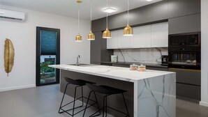A modern kitchen with a central island, black bar stools, and pendant lighting. - Villa Endless Summer - 5 Star beachfront villa with a pool by MyWaycation (Vinišće)