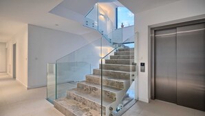 A modern staircase with glass railings and a metallic elevator. - Villa Platinum - outstanding beachfront villa with 9 bedrooms by MyWaycation (Brela)