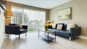 Ein modernes Wohnzimmer mit Sofa, Couchtisch und Blick durch große Fenster.