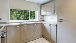 Eine moderne Küche mit großem Fenster, eingebauten Schränken und einer Spüle aus Edelstahl.