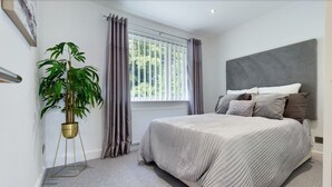 Ein Schlafzimmer mit einem Bett, einem Blumentopf, einem Fenster mit Vorhängen und einer Heizung.