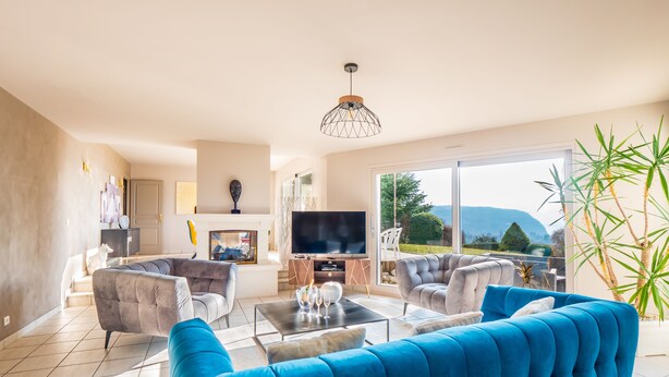 Un salon moderne avec un grand canapé bleu, un téléviseur à écran plat et une cheminée.