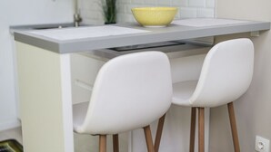 A kitchen with a white countertop, two white chairs, and a yellow bowl. - Palms Apartments Budapest (Budapest)