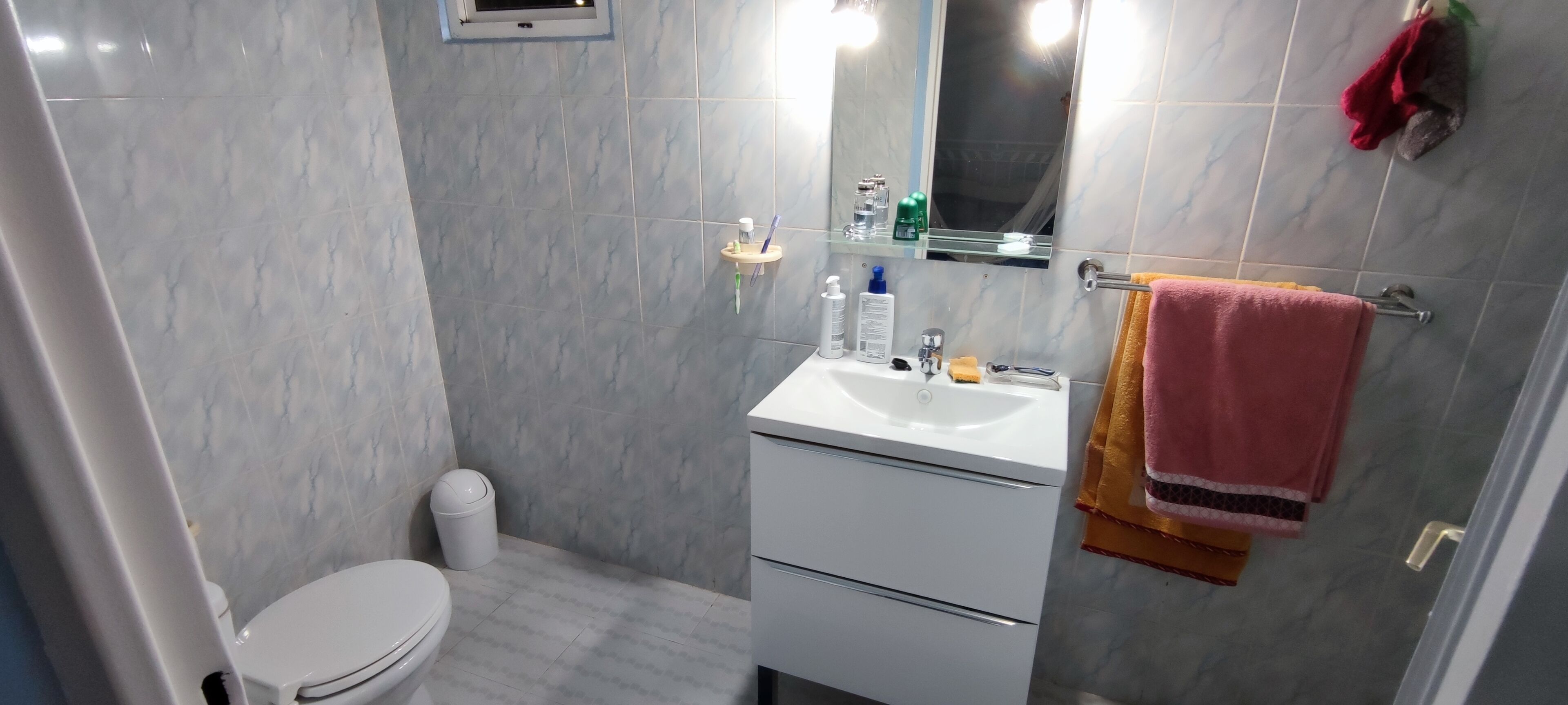 A bathroom with a toilet, sink, and mirror.
