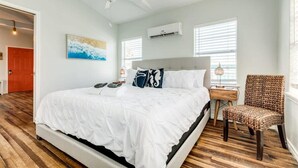 Ein Schlafzimmer mit einem großen Bett, einem Deckenventilator, einem Sessel und einem Nachttisch.