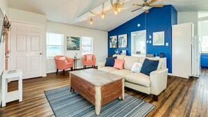 Ein Wohnzimmer mit einem Holztisch, einem beigen Sofa und einer blauen Wand.