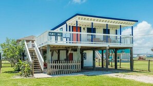 Ein zweistöckiges Gebäude mit Balkon, einer Beschilderung mit dem Schriftzug "SIX & SALT" und einer kleinen Außen-Sitzgelegenheit.