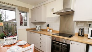 Cocina compacta con lavamanos, estufa, horno y encimera de madera.