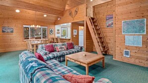 A cozy cabin interior with a wooden ceiling, a sofa set, a dining table, and a staircase. - Cabin Near Leavenworth - Deck + Pets Free (Leavenworth)
