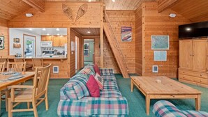A wooden cabin interior with a dining area, sofa, table, kitchen, and staircase. - Cabin Near Leavenworth - Deck + Pets Free (Leavenworth)