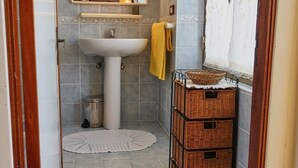 A narrow bathroom with a white sink, a mirror, and a yellow towel. There are wicker baskets on the floor. - Apartment (Santa Teresa Gallura)