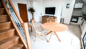 Una cocina moderna con comedor, escalera de madera y televisor de pantalla plana.