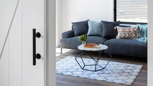 Un salon moderne avec un canapé gris, une table basse ronde et un tapis à motifs.
