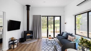 Un salon moderne avec une cheminée, un canapé, une table basse et un téléviseur fixé au mur.