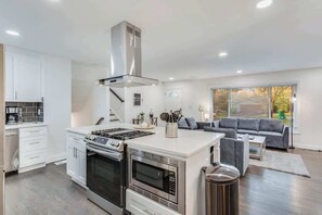 A modern kitchen with built-in appliances and a dining area with a gray sofa. - Work-ready Decatur home, sleeps 12 (Decatur)