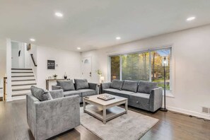 A modern living room with a grey sectional sofa, a coffee table, and a staircase leading to an upper level. - Work-ready Decatur home, sleeps 12 (Decatur)