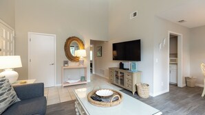 Uma sala de estar com sofá, mesa de centro com bandeja, televisão e um armário.