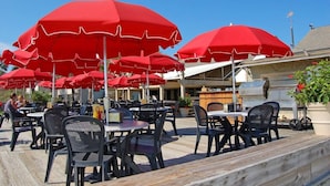 Outdoor seating with red umbrellas, tables, and chairs.