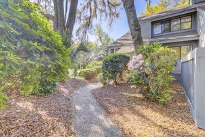 A pathway leading to a house surrounded by trees and shrubs.