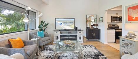 A modern living room with a sofa, coffee table, and a flat-screen TV displaying a rental advertisement.