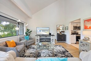 Un salon moderne avec un canapé, une table basse et un téléviseur à écran plat qui diffuse une publicité pour une location.